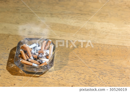 Cigarette butts in the ashtray on wooden table 30526019