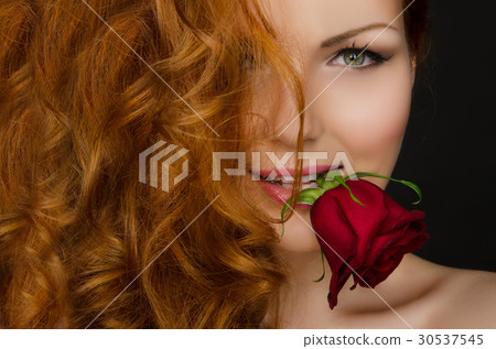 woman with red hair holds rose in her mouth woman with red hair holds rose in her mouth 30537545