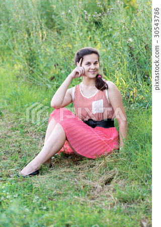 girl in red dress is sitting on the grass 30543786