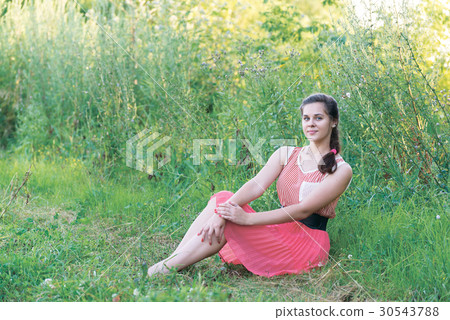 girl in red dress is sitting on the grass girl in red dress is sitting on the grass 30543788