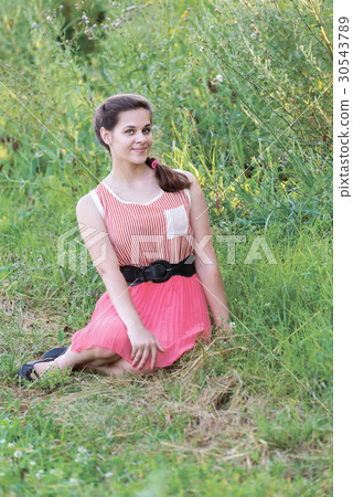 girl in red dress is sitting on the grass 30543789