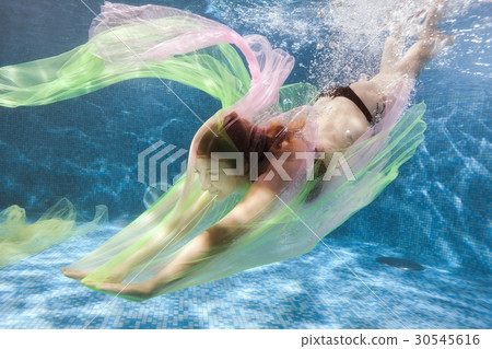 Woman swims pool and plays with colored cloth. Woman swims pool and plays with colored cloth. 30545616