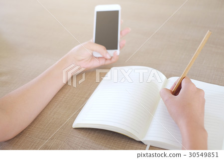 Female hand with pencil writing on a notebook  30549851