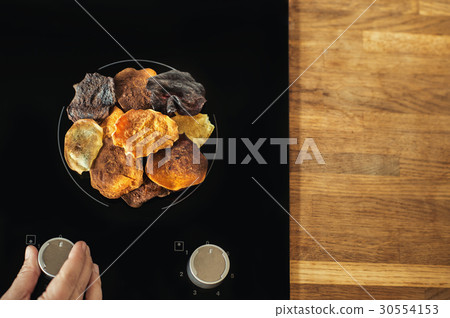 Vegetable chips lie on an electric stove and cook. 30554153