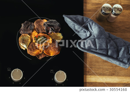 Vegetable chips lie on an electric stove and cook. 30554168