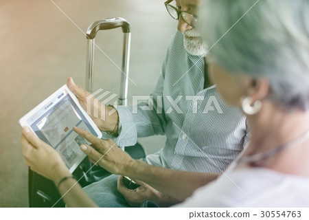 Senior adult couple checking boarding pass on digital tablet Senior adult couple checking boarding pass on digital tablet 30554763