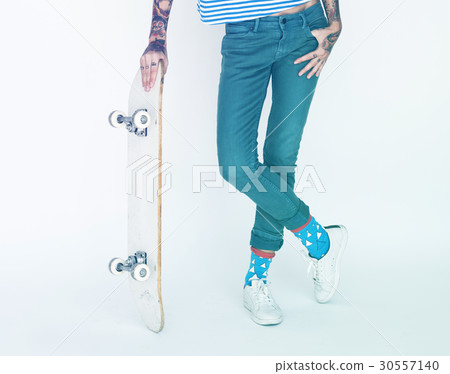 Woman standing and posing for picture with skateboard 30557140