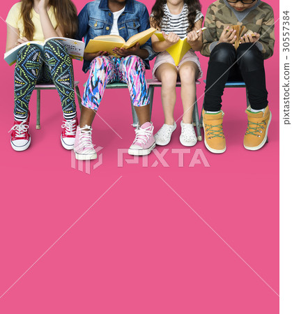 Diverse group of kids sitting in a row reading books 30557384