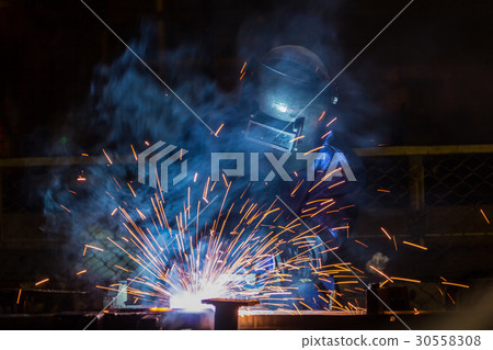 Worker in factory is welding metal part. 30558308