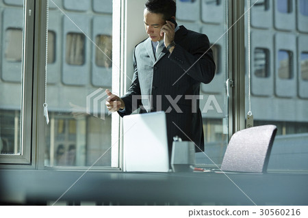 the businessman is having a phone call at office. the businessman is having a phone call at office. 30560216