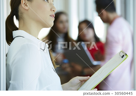 A businesswoman is holding documents and looking up. A businesswoman is holding documents and looking up. 30560445