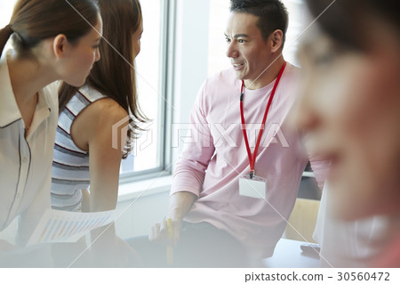 A man is smiling and talking to two women 30560472