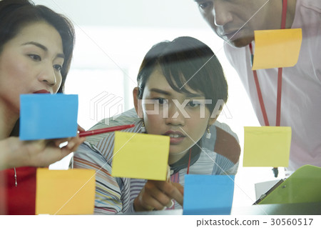 three people are pointing and looking at some stickers three people are pointing and looking at some stickers 30560517