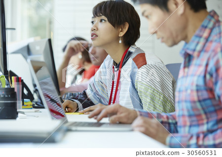 A woman is looking at something while colleagues are working A woman is looking at something while colleagues are working 30560531