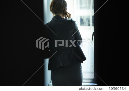 Rear view of a businesswoman talking on phone in office. 30560584