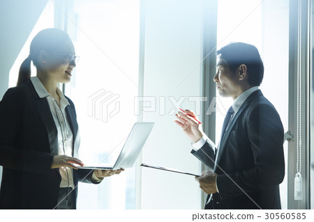 Two business people are talking and discussing in the office. Two business people are talking and discussing in the office. 30560585