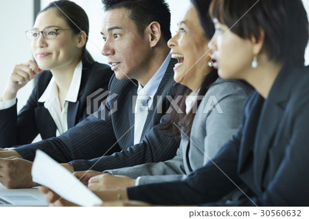 Four people are smiling and concentrating on something in office. 30560632