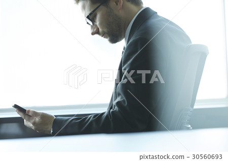 a portrait of a businessman looking at his phone a portrait of a businessman looking at his phone 30560693