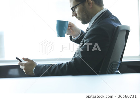 a portrait of a man sitting, drinking and looking at a phone a portrait of a man sitting, drinking and looking at a phone 30560731