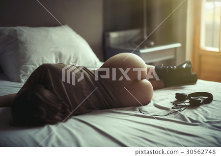 Beautiful naked girl lies on a bed in headphones  30562748
