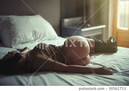 Beautiful naked girl lies on a bed in headphones  30562753