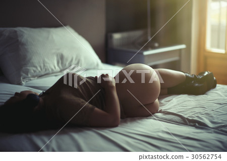 Beautiful naked girl lies on a bed in headphones  30562754