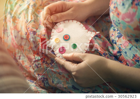 Female hands sew white cotton heart with buttons 30562923