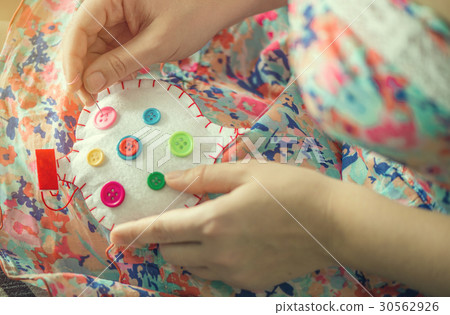 Female hands sew white cotton heart with buttons Female hands sew white cotton heart with buttons 30562926