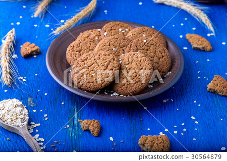 Oatmeal cookies in brown plate on blue background Oatmeal cookies in brown plate on blue background 30564879