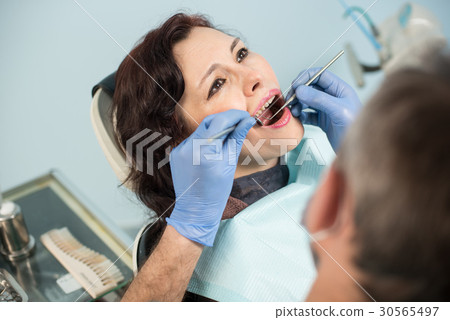 Dentist examining patient's teeth in dental office Dentist examining patient's teeth in dental office 30565497