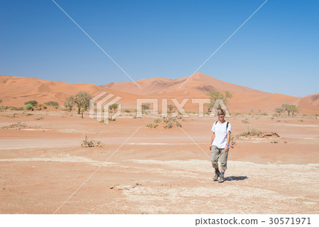 Tourist walking on the dunes of Sossusvlei 30571971