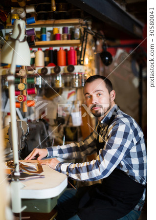 Male worker stitching new belt Male worker stitching new belt 30580041