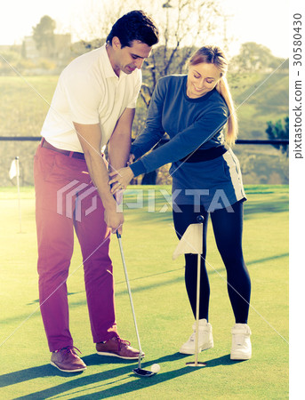 Woman golfer training man to play golf 30580430