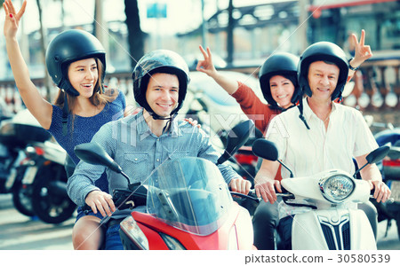 Young and mature couples driving petrol scooters Young and mature couples driving petrol scooters 30580539