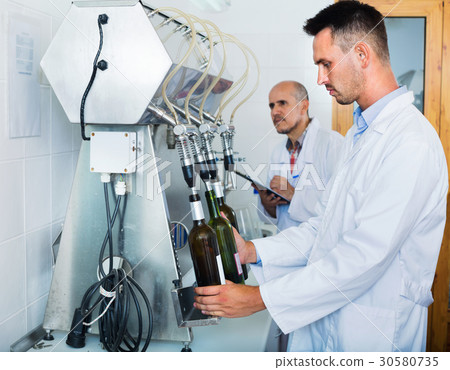 Portrait of male winery worker with bottling machinery on factory 30580735