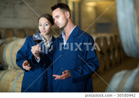 Two expert in uniform looking at wine sample in glass Two expert in uniform looking at wine sample in glass 30580942