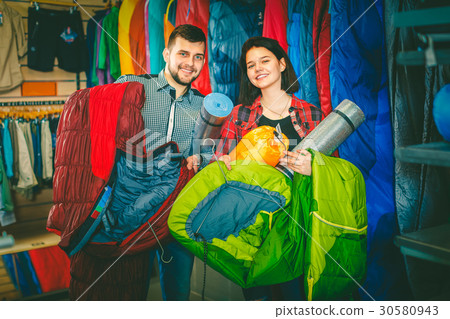 Couple examining touristic equipment items Couple examining touristic equipment items 30580943