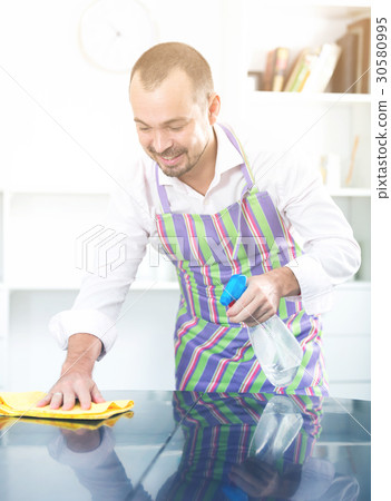Young man in apron cleaning table 30580995