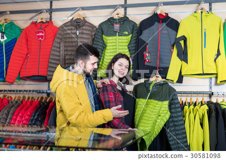 Positive couple deciding on windcheater in store 30581098