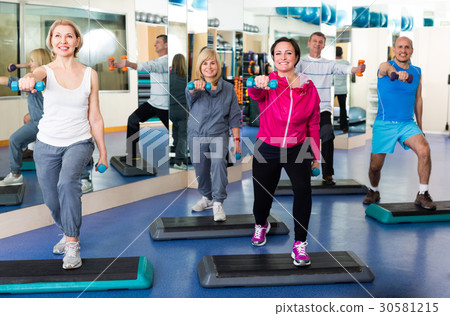 Group training in gym with dumbbells. Group training in gym with dumbbells. 30581215