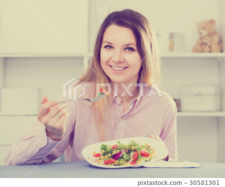 Young positive woman trying tasty green salad Young positive woman trying tasty green salad 30581301