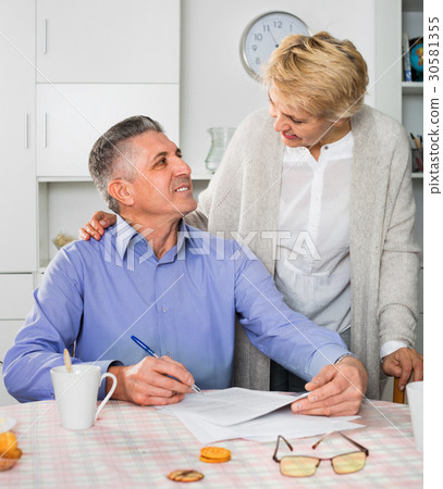 Mature married couple discuss contract and sign important documents 30581355