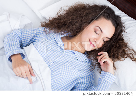 Curly haired girl having a nap in bed 30581404