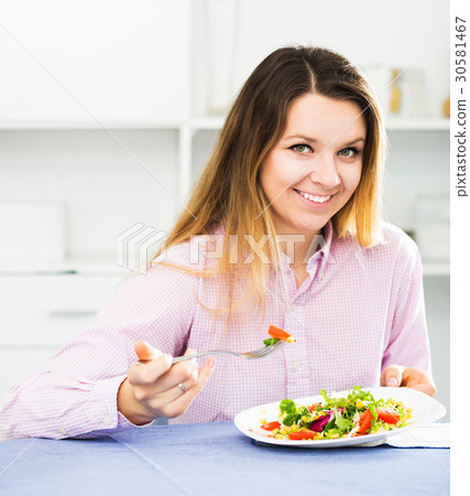 Girl eating green salad 30581467
