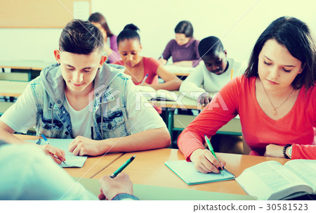 Enthusiastic girls and boys taking the notes while 30581523