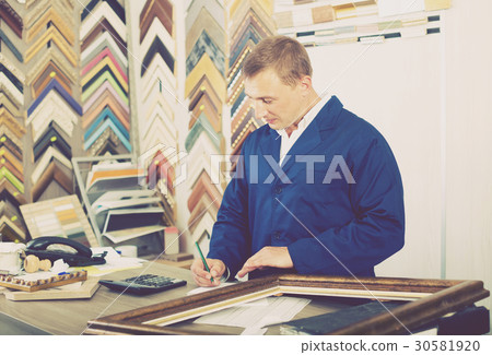 portrait of man seller working with picture frames in atelier portrait of man seller working with picture frames in atelier 30581920