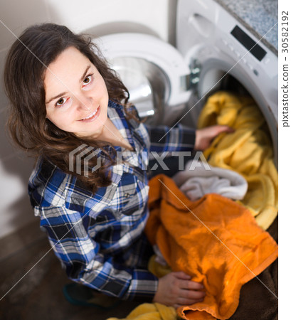 young brunette doing laundry in kitchen and smiling young brunette doing laundry in kitchen and smiling 30582192