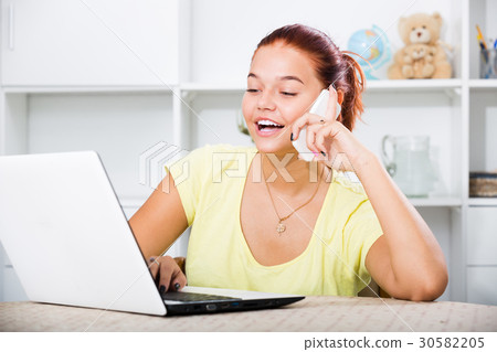 girl chatting on phone and typing on laptop. 30582205