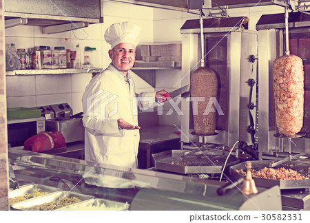 mature chef slicing kebab in fast food. mature chef slicing kebab in fast food. 30582331