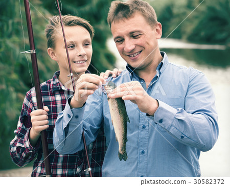 Positive man with son looking at fish on hook 30582372